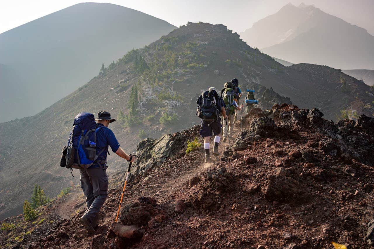 about-02 Group of hikers trekking on a rugged mountain trail in Oregon's scenic outdoors.