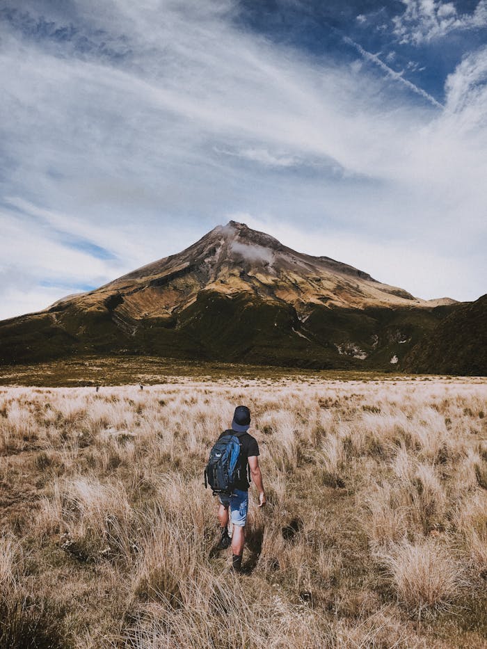 why-choose-us-02 A backpacker walks towards a scenic mountain under a dramatic sky.