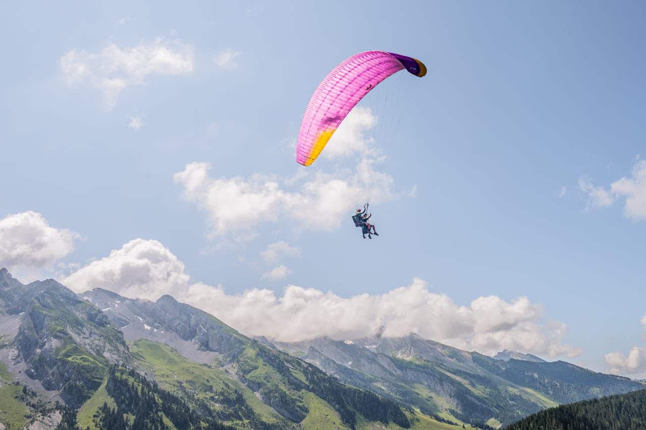 services-02 Experience the thrill of paragliding over the stunning Alps on a bright day.
