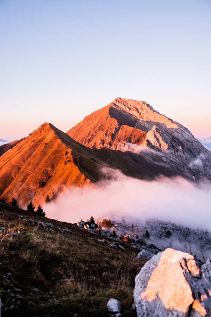 about-04 Breathtaking view of sunlit peaks and misty valleys in the Alps at sunset.